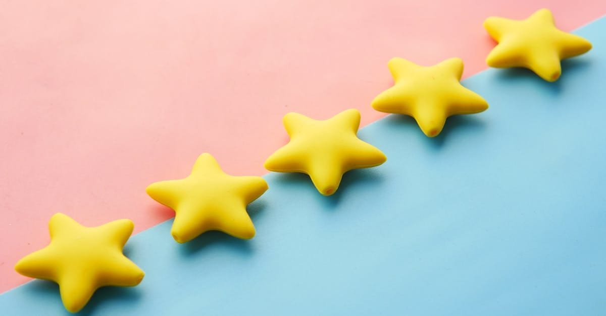 Yellow stars on pink and blue pastel background for rating or review concept.