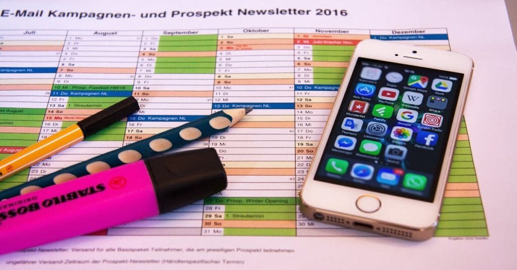A desk setup featuring a planner, pens, and a smartphone displaying app icons, ideal for productivity.