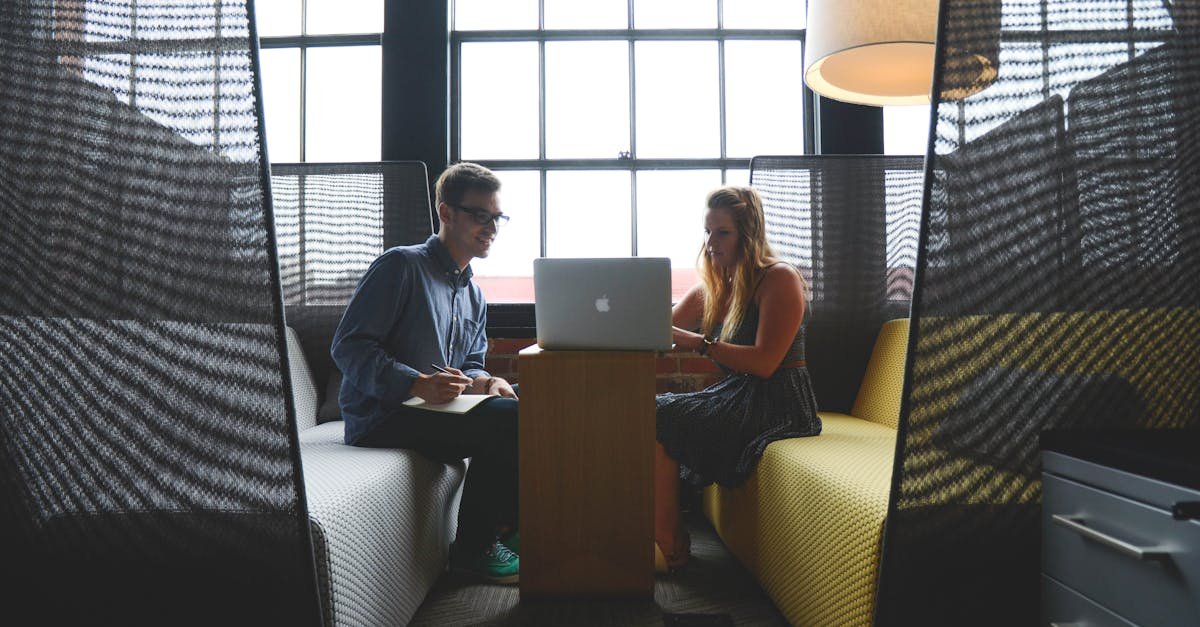Two adults discussing work and collaborating in a modern office lounge area.