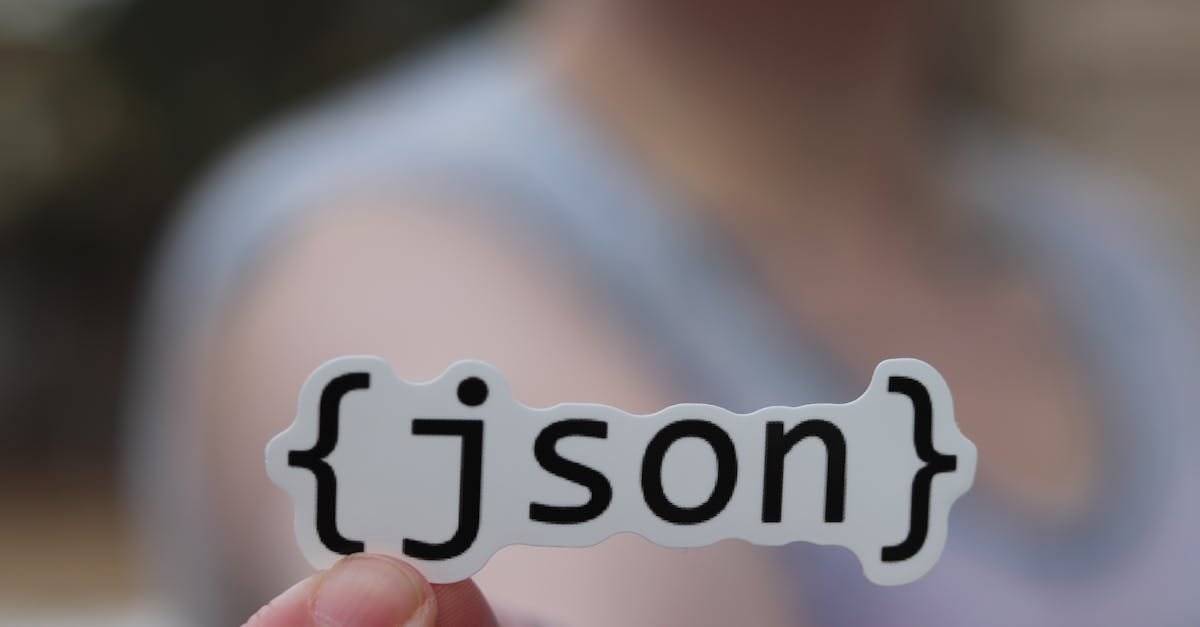 A hand holding a JSON text sticker, symbolic for software development.
