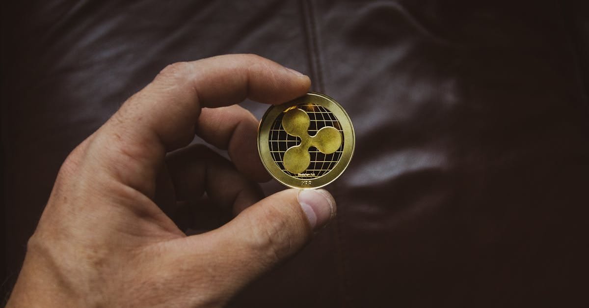 A close-up of a hand holding a gold Ripple cryptocurrency coin, symbolizing digital currency concept.
