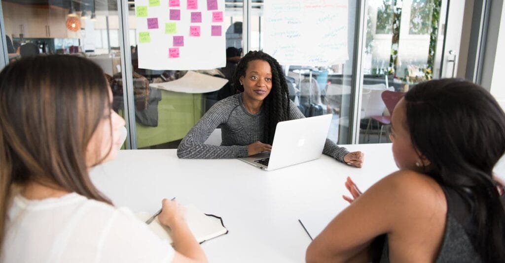 A diverse group of women collaborates around a desk in a modern office setting.