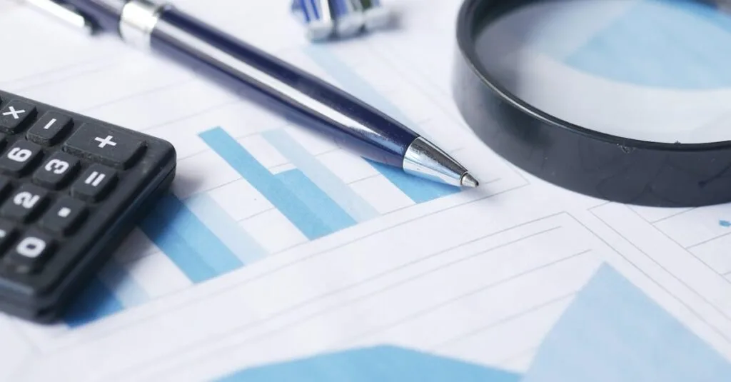 Close-up of calculator, pen, and magnifying glass on financial documents.