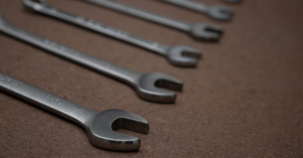A detailed photo of silver metallic spanners laid on a brown surface.