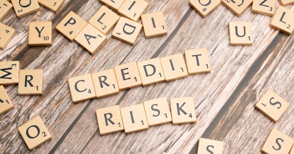 Scattered wooden letter tiles spelling 'credit risk' on a rustic wooden surface.