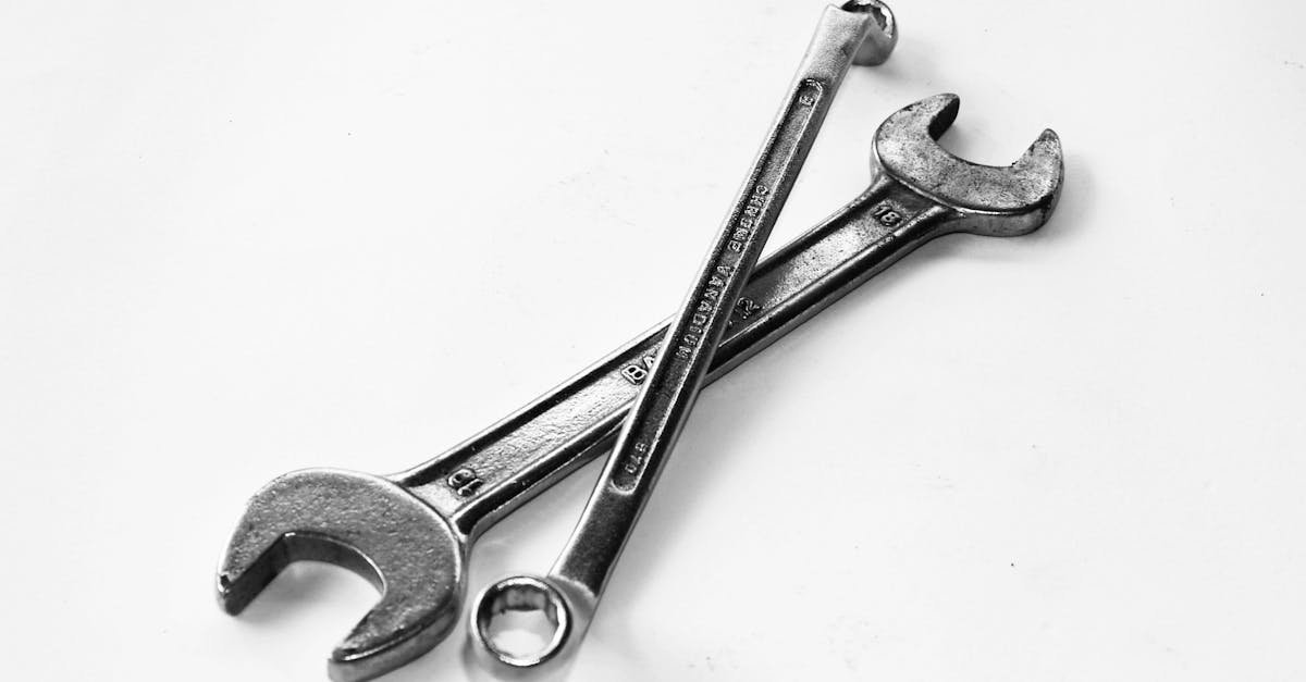 A pair of crossed metal wrenches on a clean white surface.
