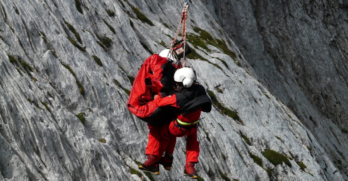 Two rescuers in action on a mountain, showcasing teamwork and safety in a daring lift.
