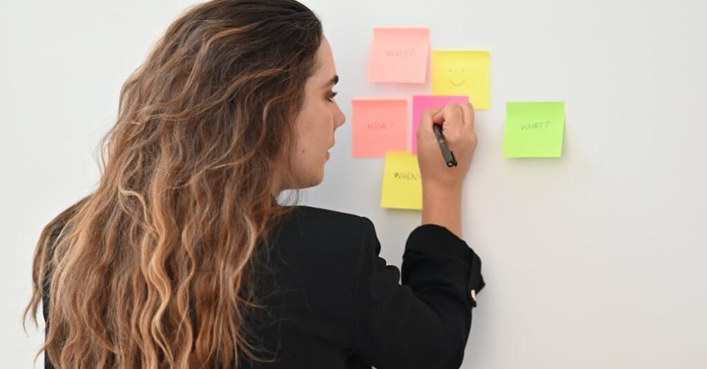 Professional woman writing on colorful sticky notes, optimizing workflow in office setting.