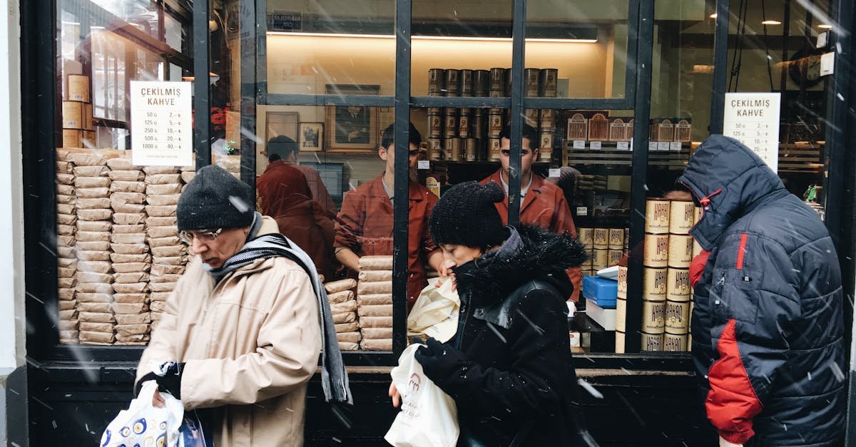 People purchasing coffee from a street vendor during a snowy day.