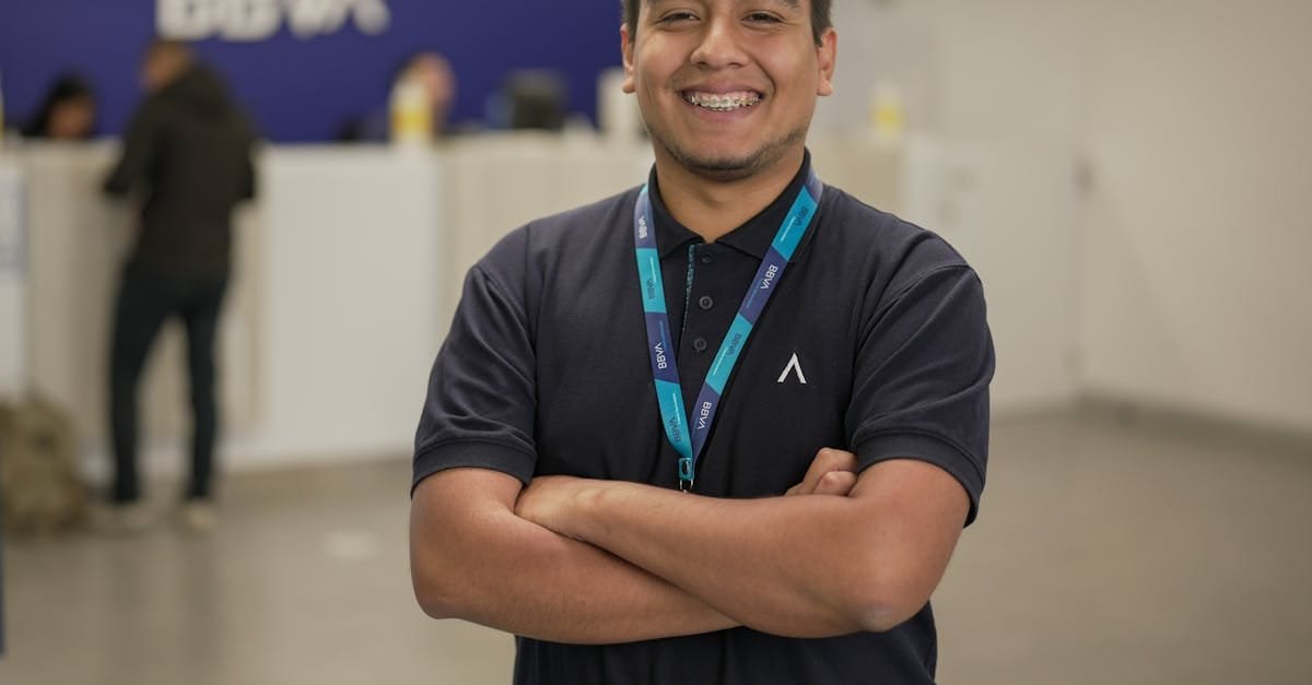 Confident bank employee standing with arms crossed at BBVA reception area, smiling warmly.