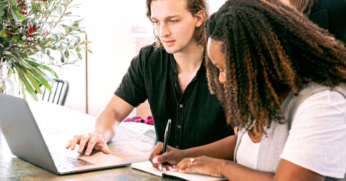 Young professionals collaborating on a project in a modern office with laptop and notes.