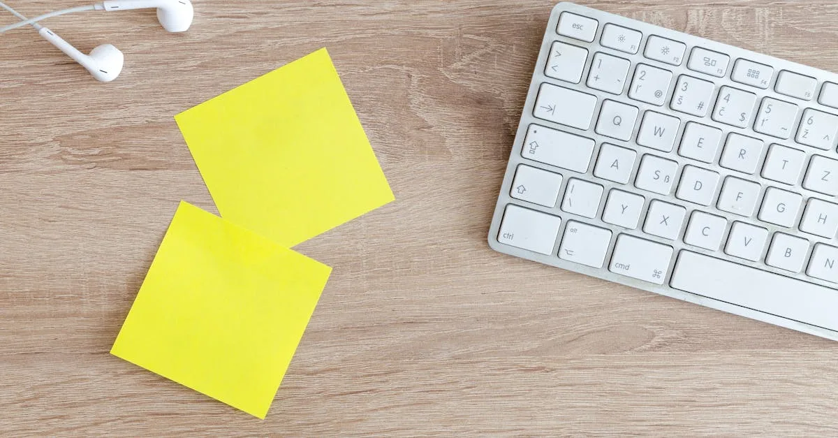 Top view of a workspace with a keyboard, earphones, and yellow sticky notes on a wooden desk.