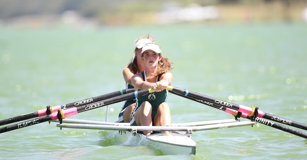 Focused female rower engaged in a competitive rowing event on a sunny day.