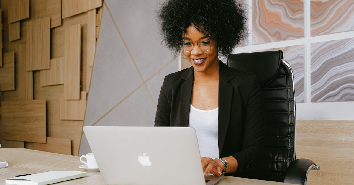 Smiling woman working remotely on a laptop in a stylish office setting.