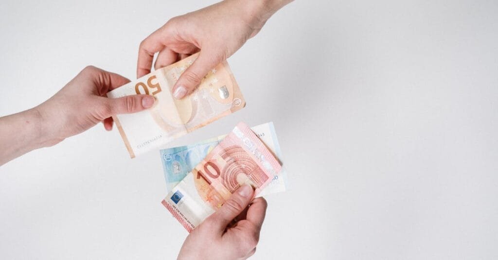 Close-up of hands exchanging euro bills, symbolizing finance and transaction.