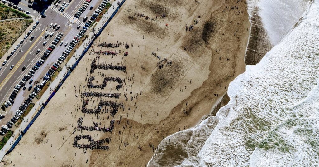 A large group on a beach forms the word "Resist" in powerful demonstration.