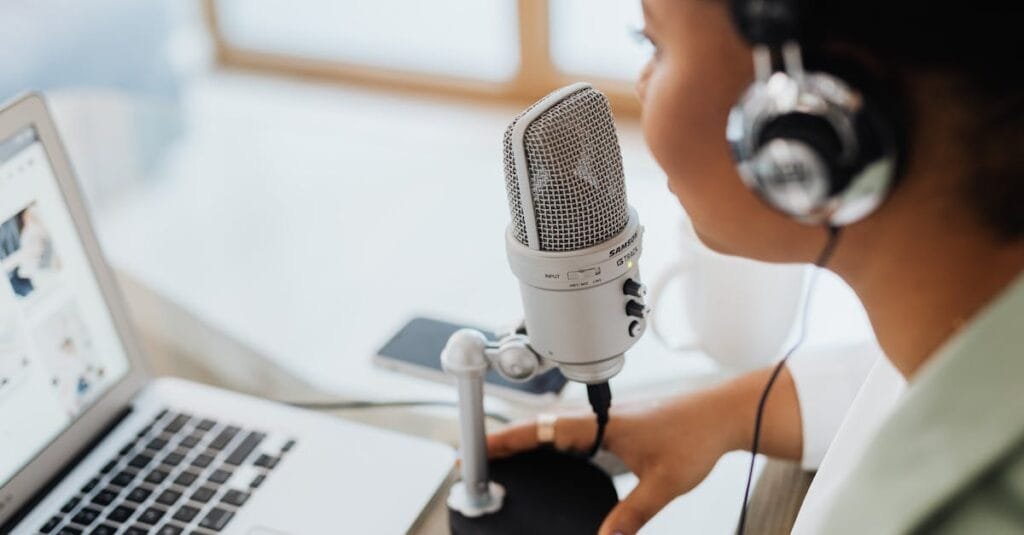 Professional woman recording a podcast or broadcast using a microphone and laptop at a desk.