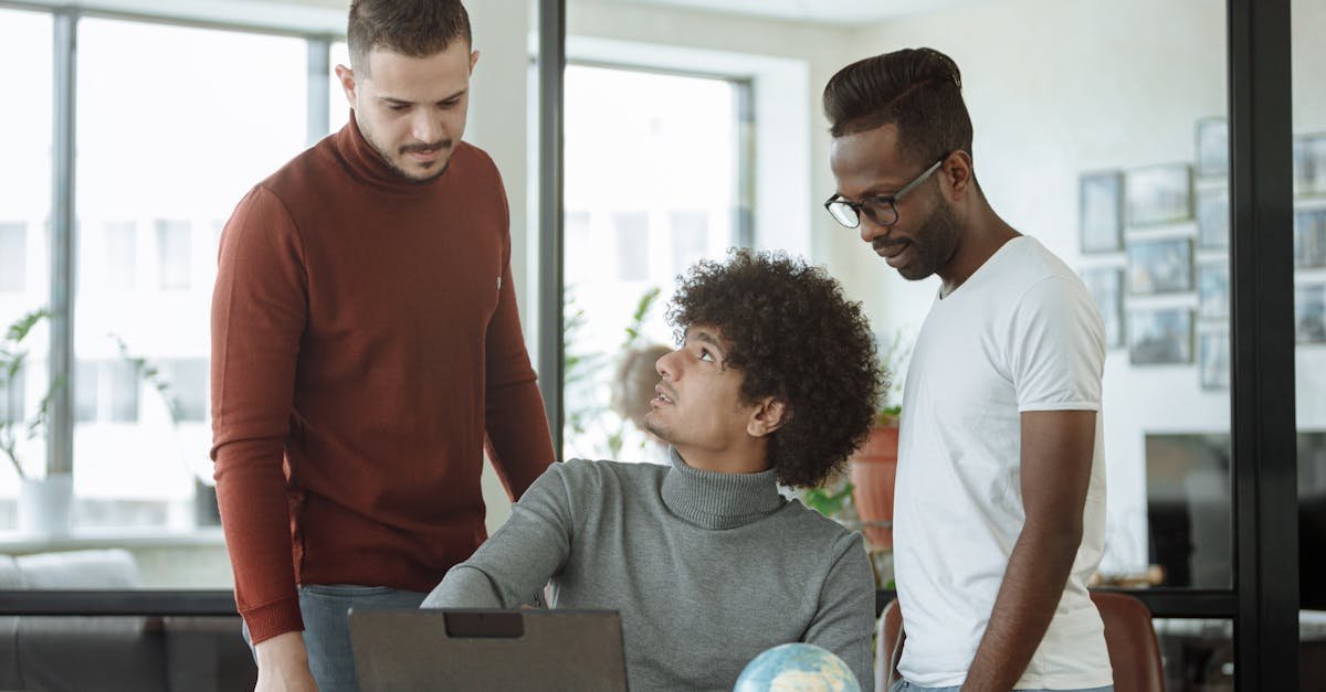 Three colleagues discussing a project with a laptop and a globe in a modern office setting.