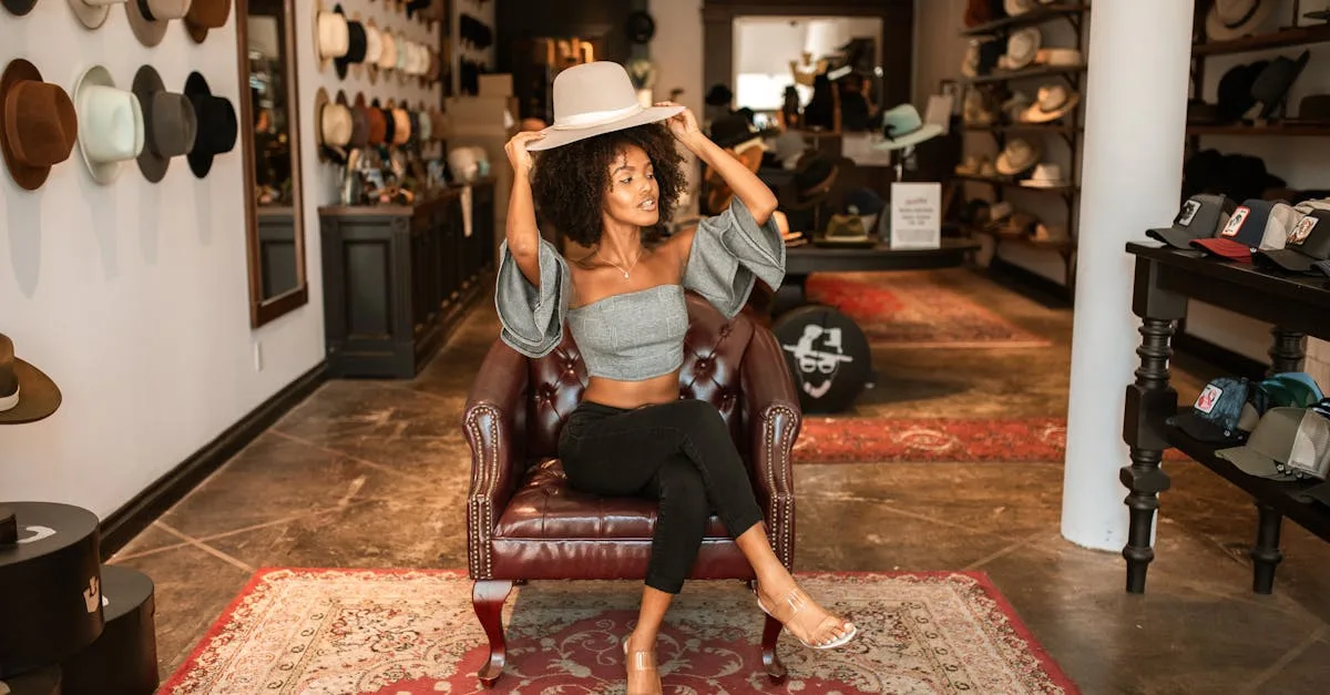 A woman in a chic boutique tries on hats while sitting on a leather chair, showcasing a fashionable interior.