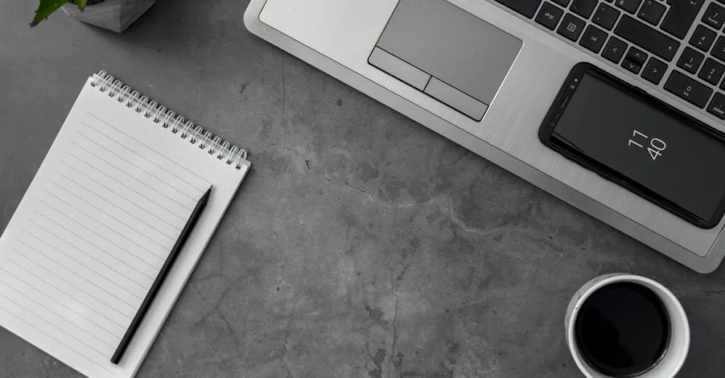 Minimalist workspace featuring laptop, smartphone, notepad, pencil, and coffee cup for productivity.
