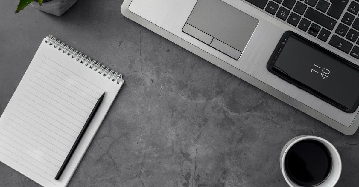 Minimalist workspace featuring laptop, smartphone, notepad, pencil, and coffee cup for productivity.
