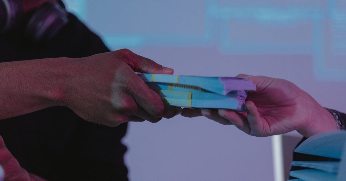 Close-up of hands exchanging money, highlighting financial exchange in a dimly lit setting.