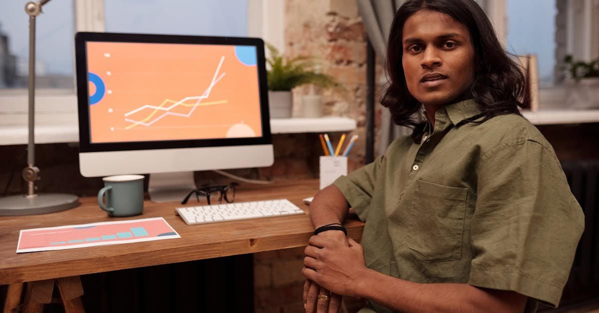 A young professional working in a home office setting, analyzing data charts on a computer screen.