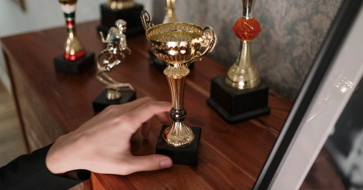 A close-up of a hand reaching for a shiny trophy on a wooden shelf, symbolizing success.