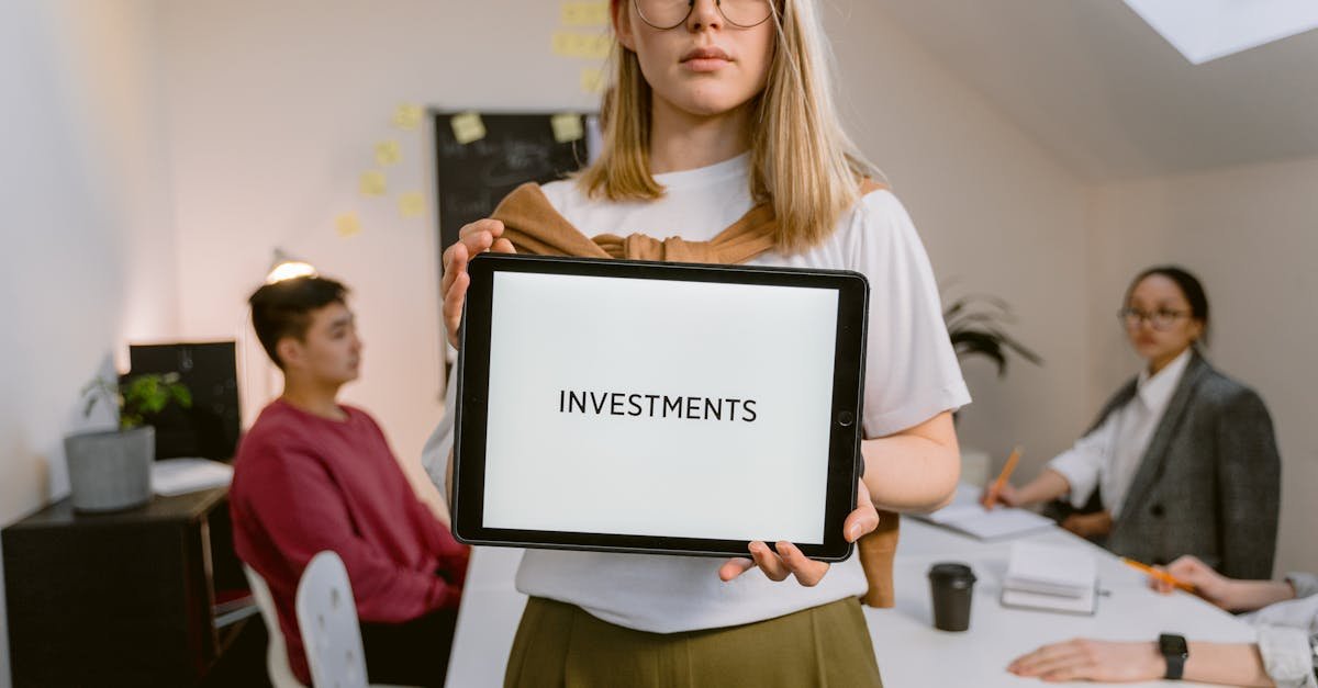 Young professional holding tablet in team meeting focused on investments.