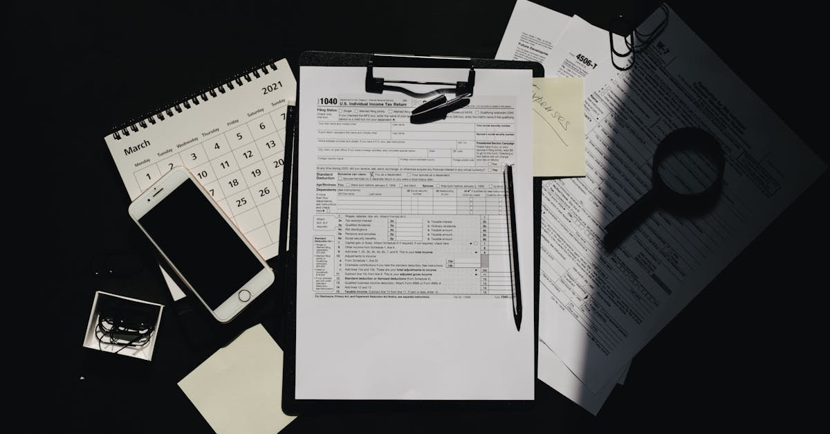 Flat lay of tax documents, calendar, and smartphone on a dark surface, symbolizing tax preparation.