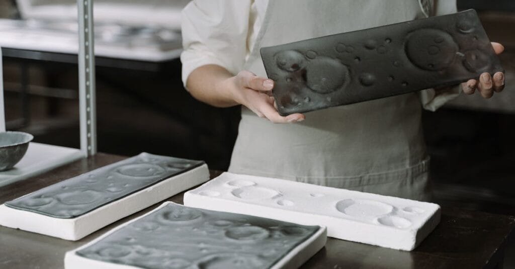 Artisan showcasing handcrafted ceramic plates in an artisanal workshop setting, highlighting craftsmanship.