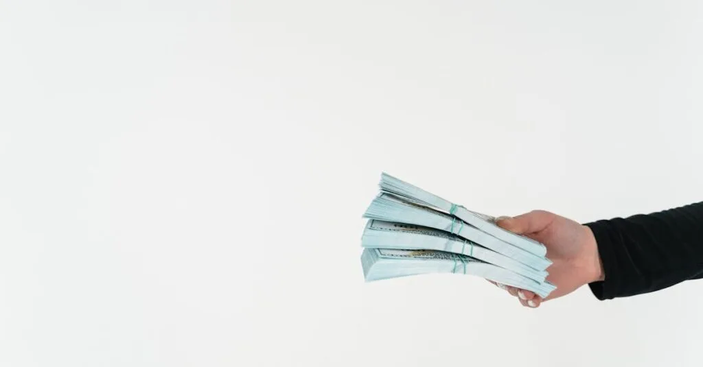 Close-up of a hand holding bundles of American dollar bills against a white background.