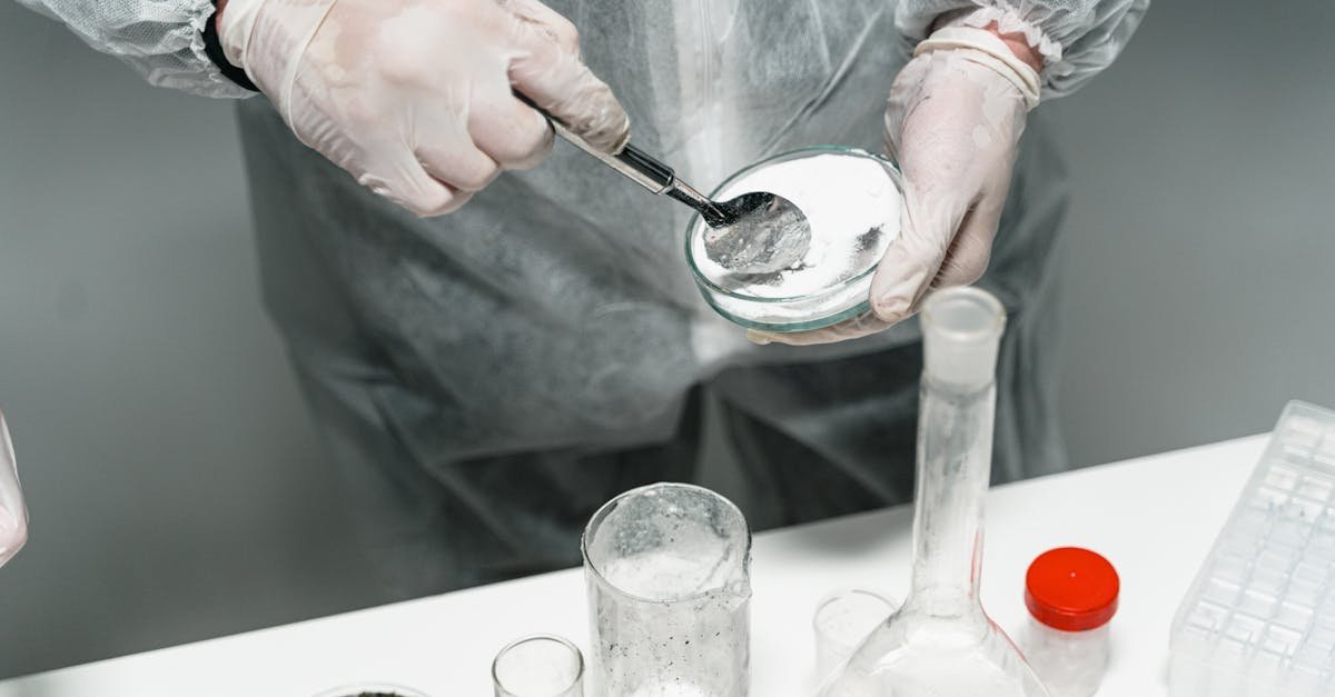 Scientist in protective gear handling powder sample in a sterile lab environment.