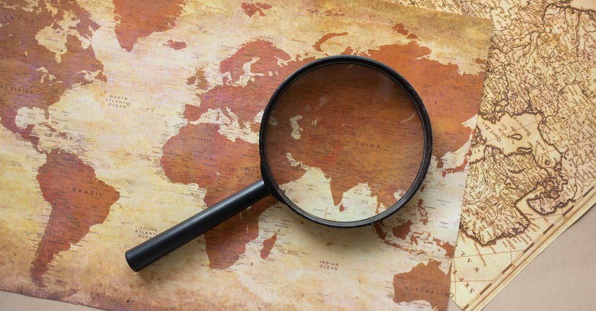 A top view of a vintage world map with a magnifying glass highlighting regions for exploration.