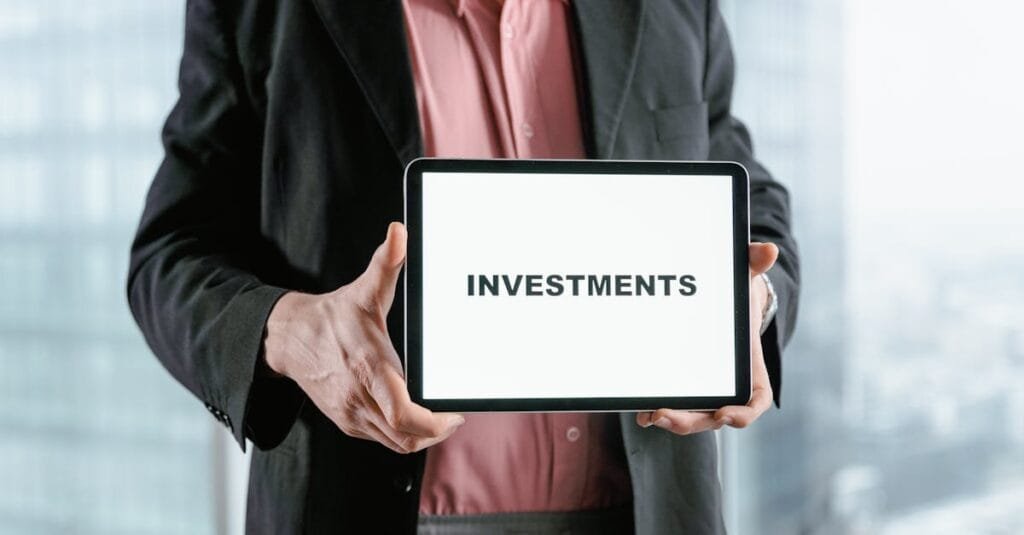 Professional holding a tablet with 'INVESTMENTS' text, ideal for finance and business themes.