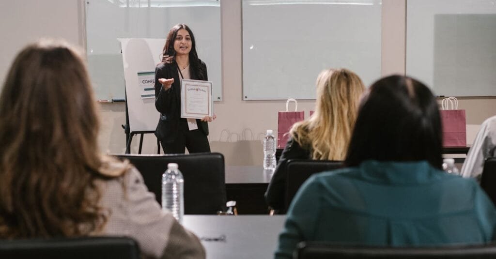 A business seminar showcasing a female presenter awarding certificates to attendees.