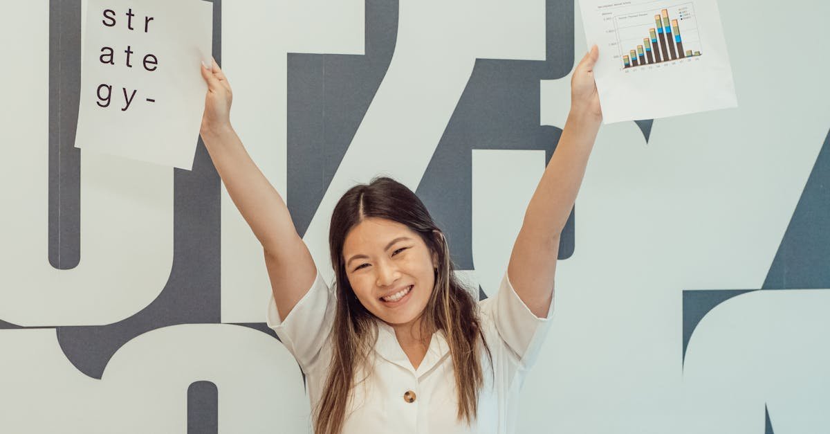 Smiling woman raises hands with strategy and graph papers, celebrating business success.