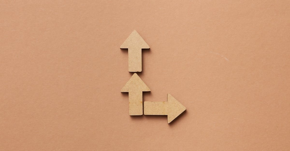 Three cardboard arrows arranged on a brown background, symbolizing direction and choice.