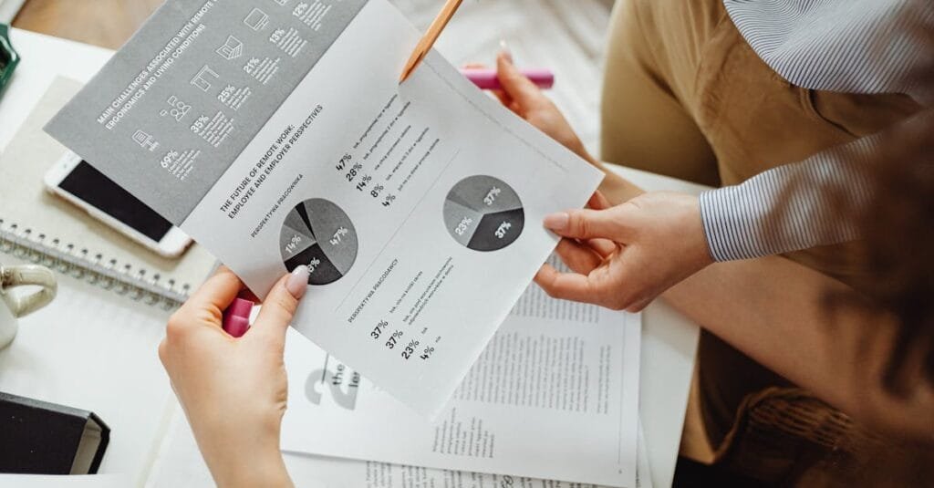 Two people reviewing financial reports and graphs at a desk for analysis and decision-making.