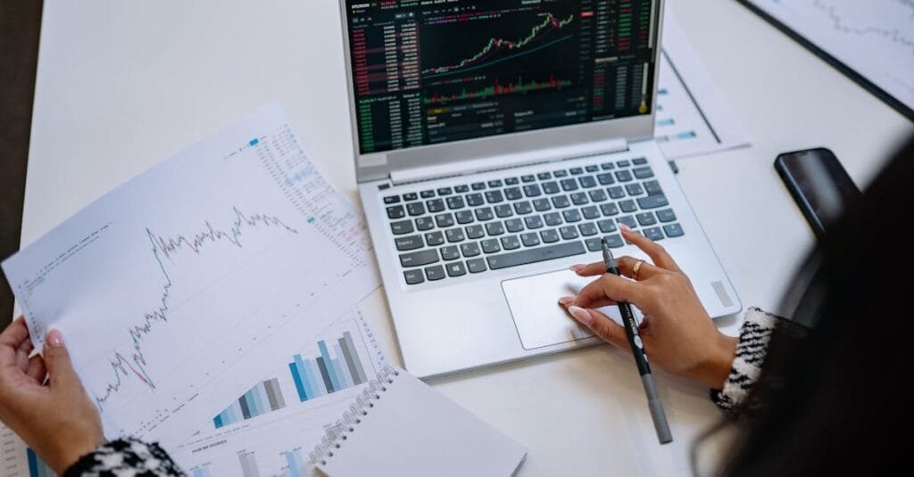 A detailed look at business analysis with a laptop displaying graphs and financial charts on a table.
