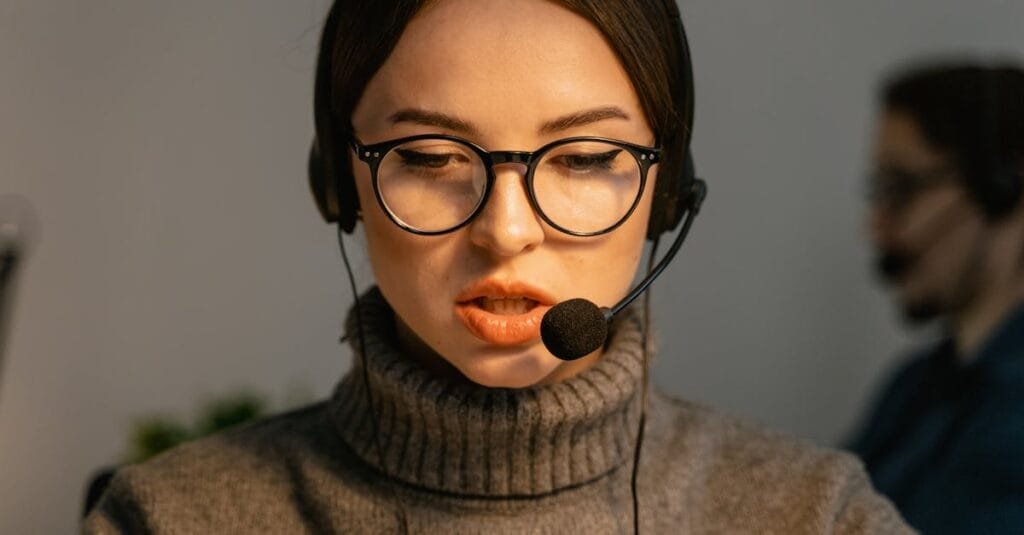 Close-up of a focused call center agent with eyeglasses and headset providing customer support.