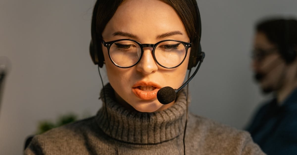 Close-up of a focused call center agent with eyeglasses and headset providing customer support.