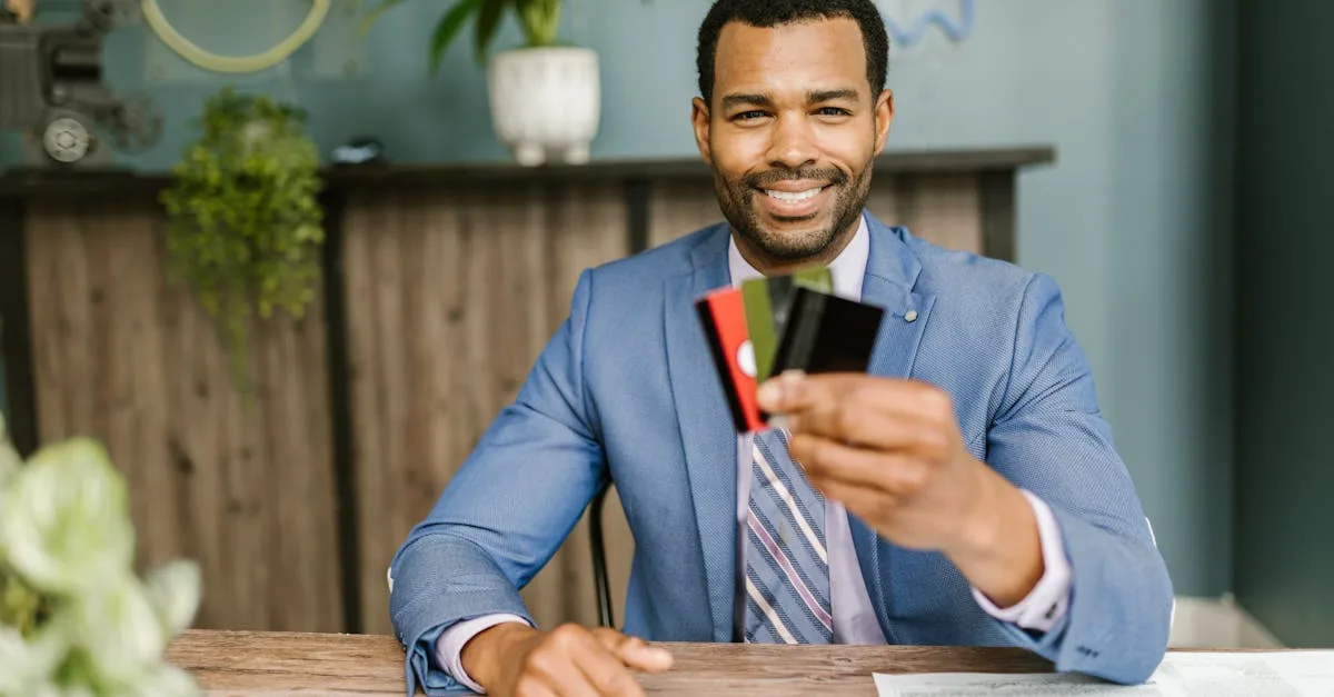 Smiling African American man in a suit holding credit cards at a business desk.