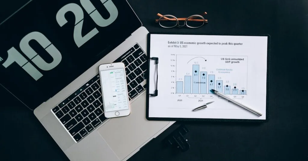 Top view of financial analysis tools on a desk including a laptop, smartphone, and graphs.