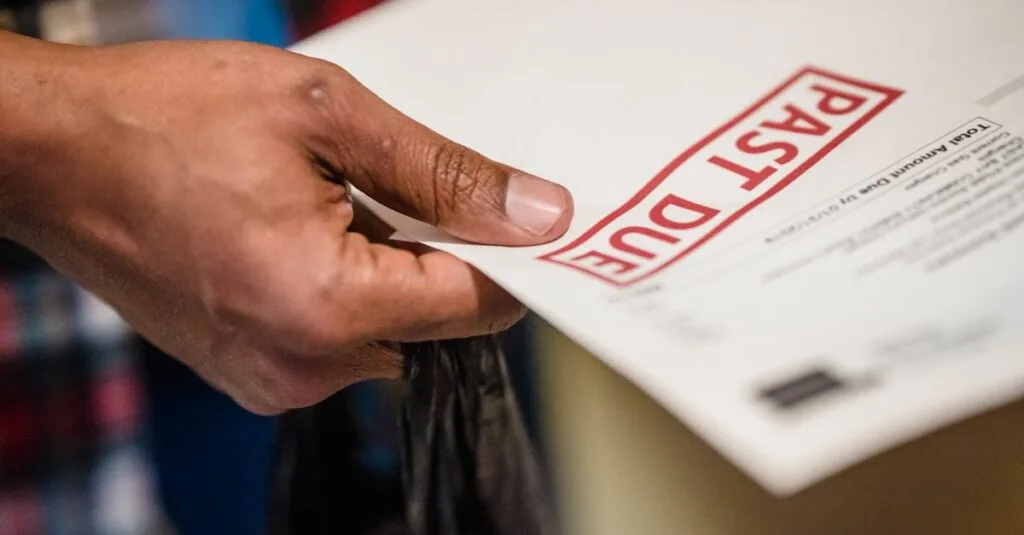 A close-up of a hand holding a document with a 'Past Due' stamp, highlighting financial urgency.