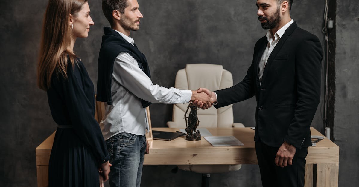 Three business professionals engage in a formal handshake in a modern office setting.