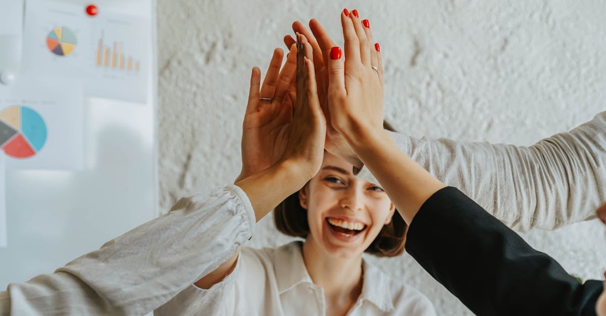 Happy colleagues high-fiving in a meeting, showcasing teamwork and success.