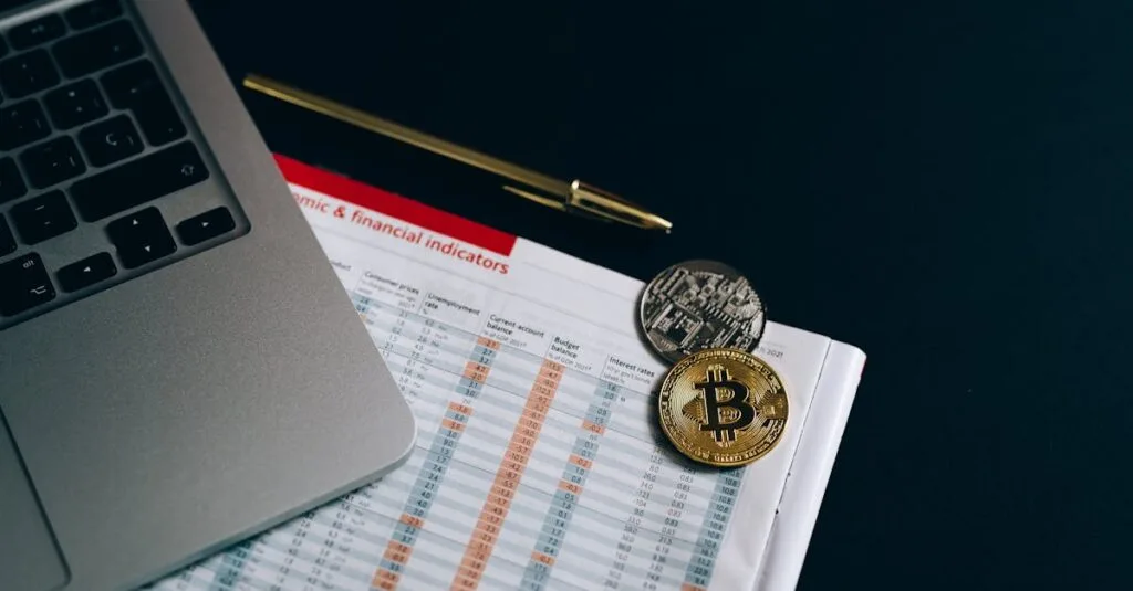 Bitcoin and cryptocurrency coins placed on a financial document next to a laptop.