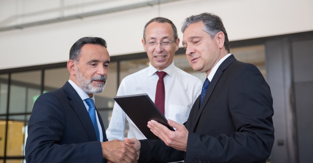 Professional men engaging in teamwork with a digital tablet in a modern office environment.