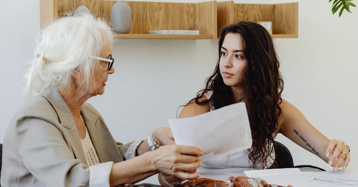 Elderly woman and young woman discussing fabric designs in a fashion meeting.